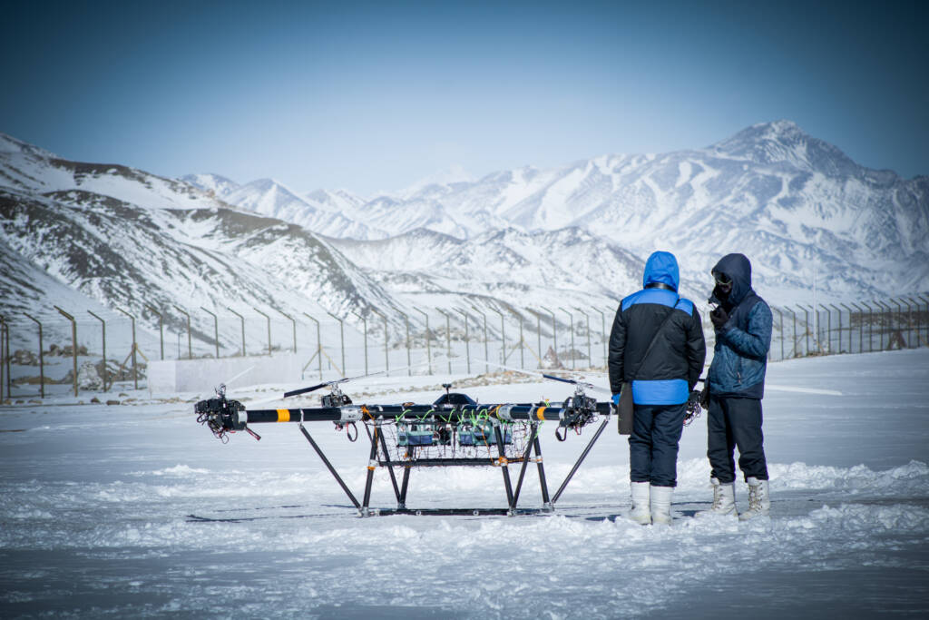 EndureAir UAV on snow with two operators and mountains behind