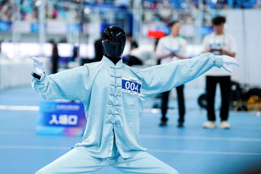 AgiBot A3 humanoid in a light blue tai chi uniform, bib 004, arms extended