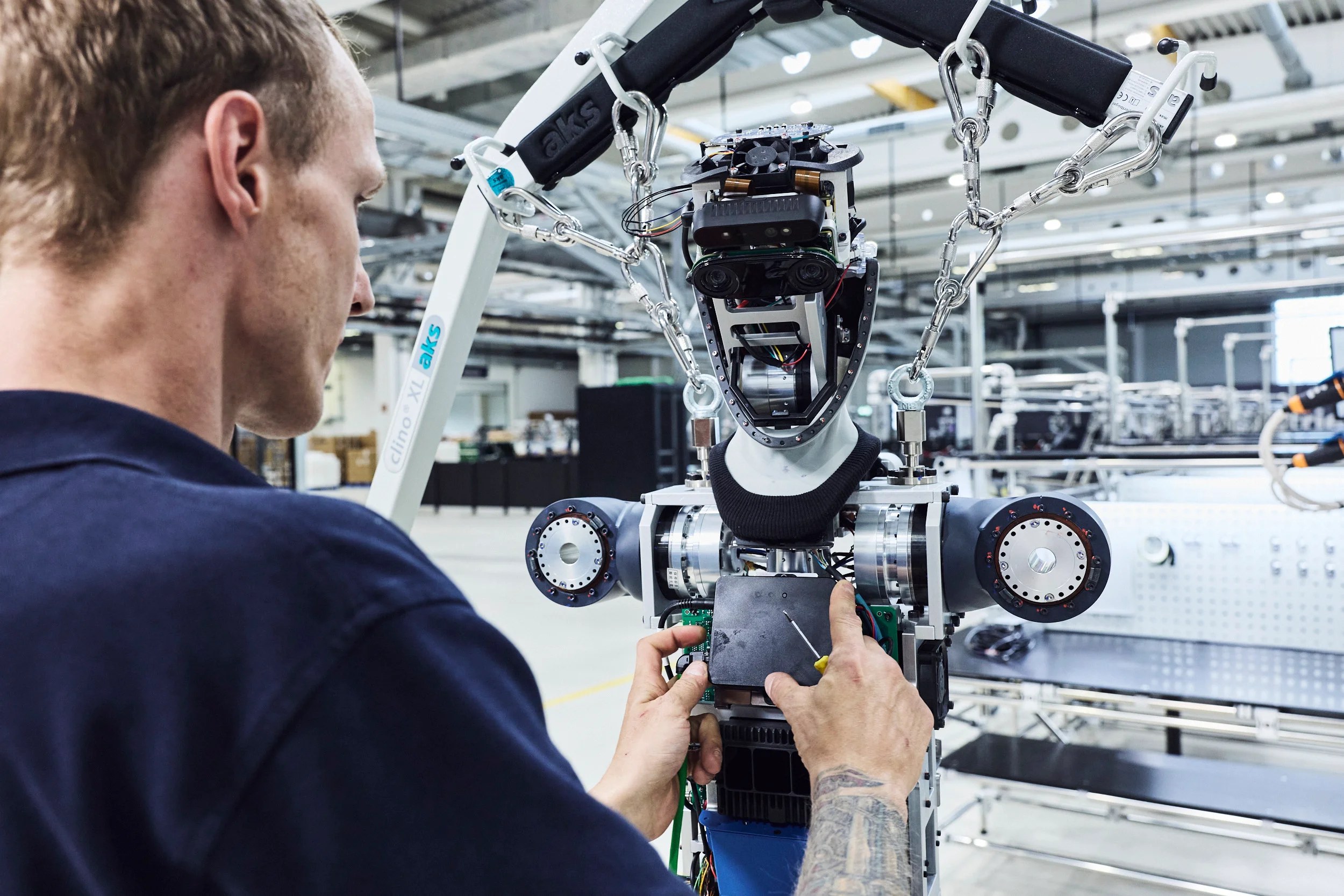 Technician installing torso electronics on an Agile ONE suspended from a lift rig