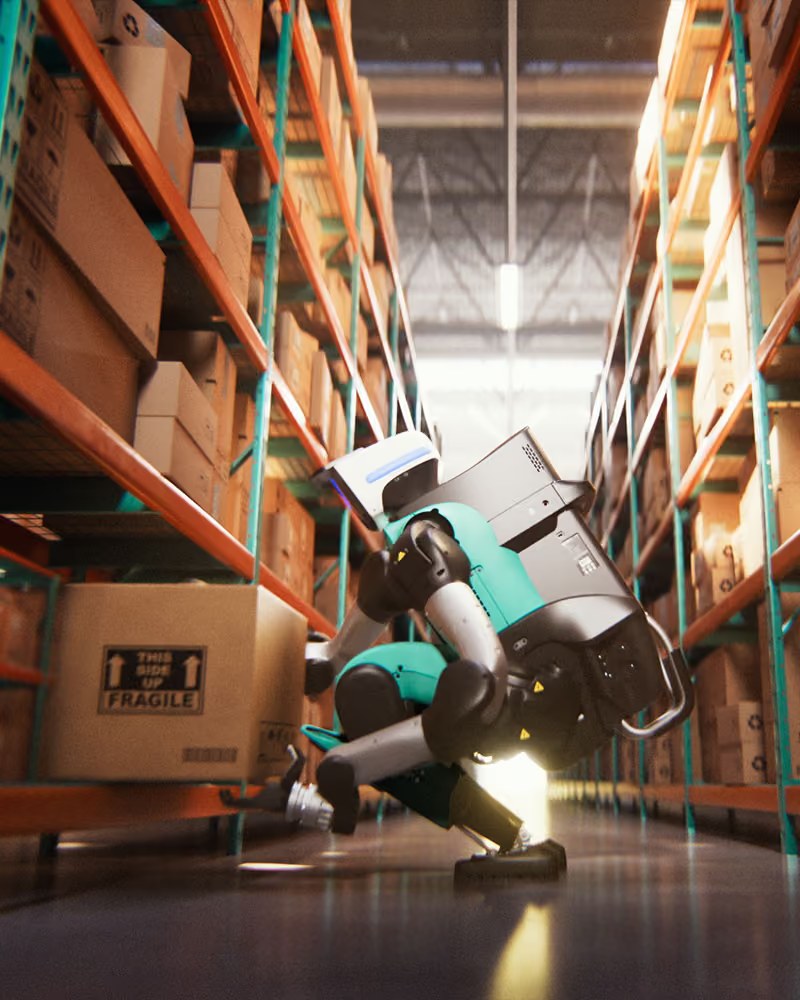 Digit 5 squatting in a warehouse aisle to lift a cardboard box labeled fragile