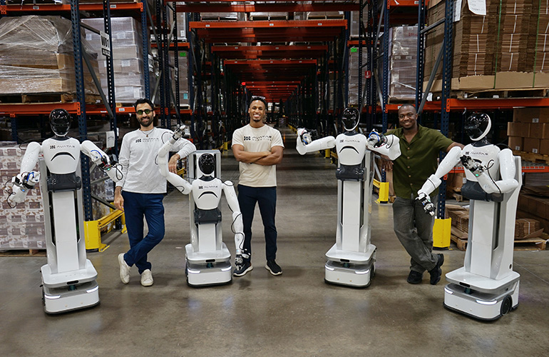 Avatar Robotics team with white wheeled humanoid robots in a warehouse aisle