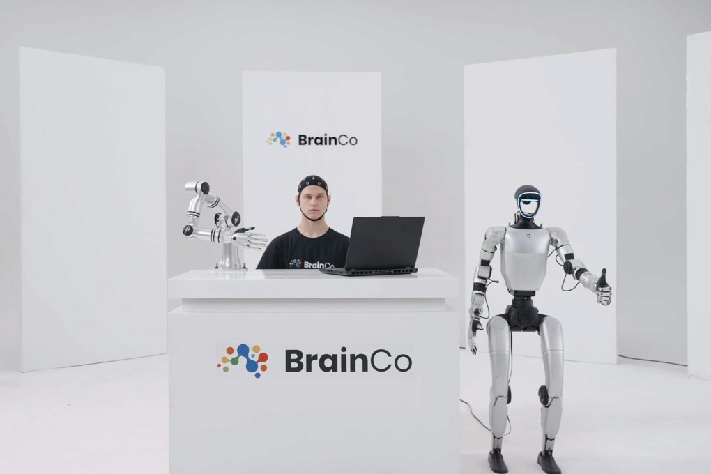 Person wearing BrainCo EEG headset with robotic arm and humanoid on stage