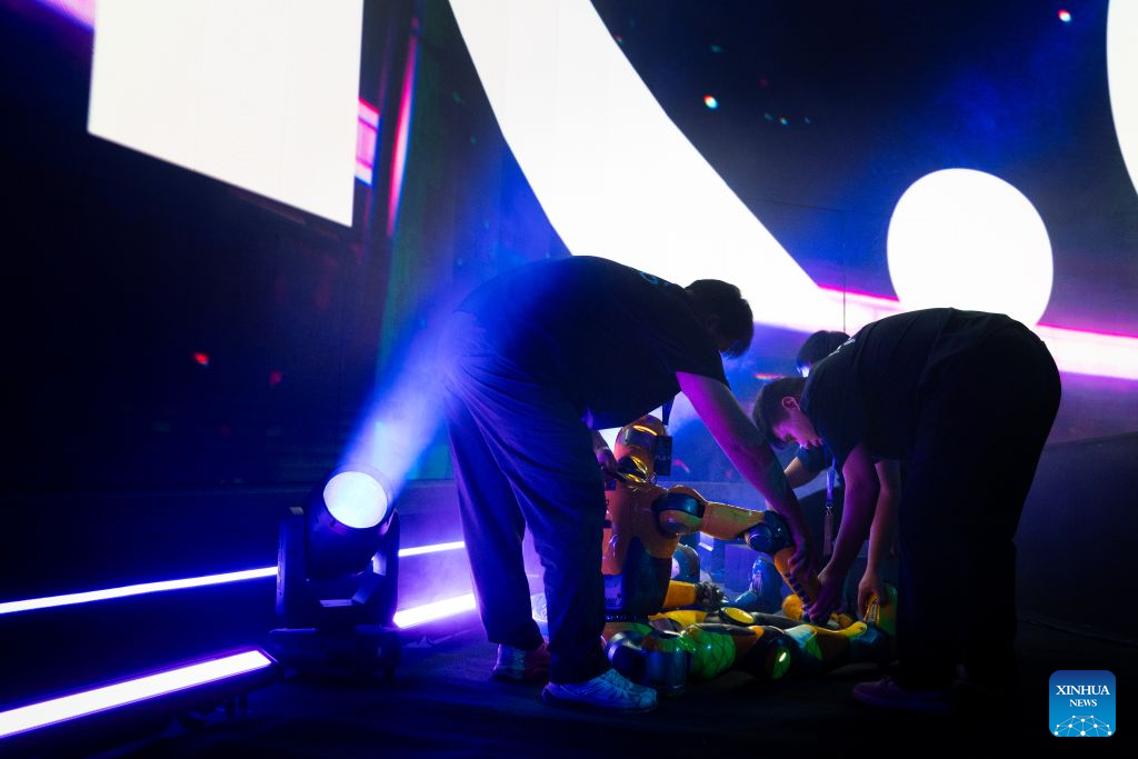 Technicians kneeling over a yellow T800 between rounds under stage lights