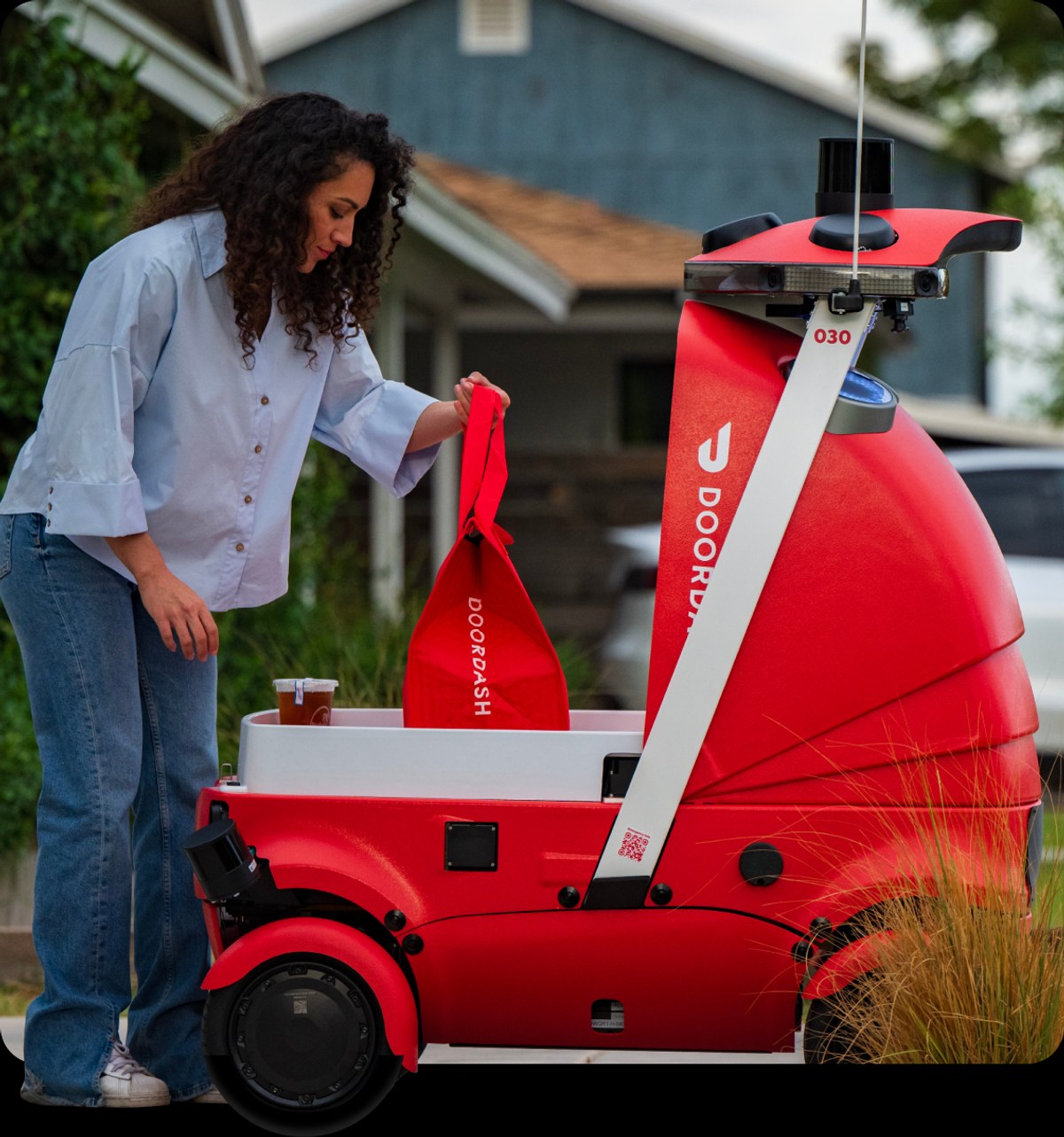 DoorDash Dot robot on a street next to a person