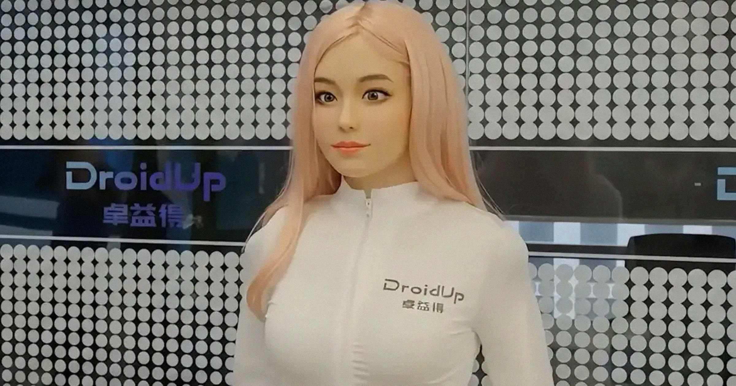 DroidUp Moya biomimetic humanoid with pink hair and company logo backdrop