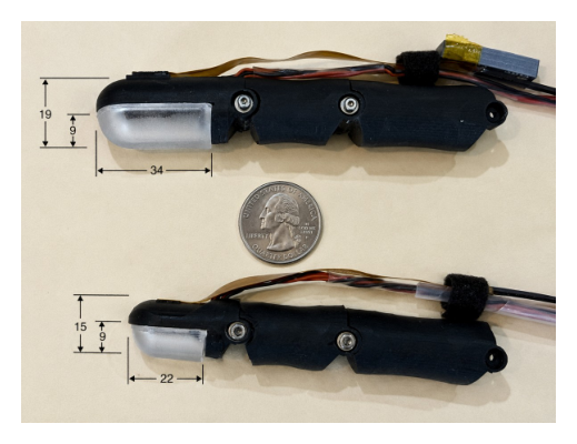 Two black rounded tactile robot fingers next to a US quarter for scale