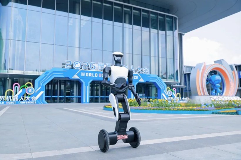 White-and-black wheel-legged GoMate Mini standing in front of the 2026 World Robot Conference hall