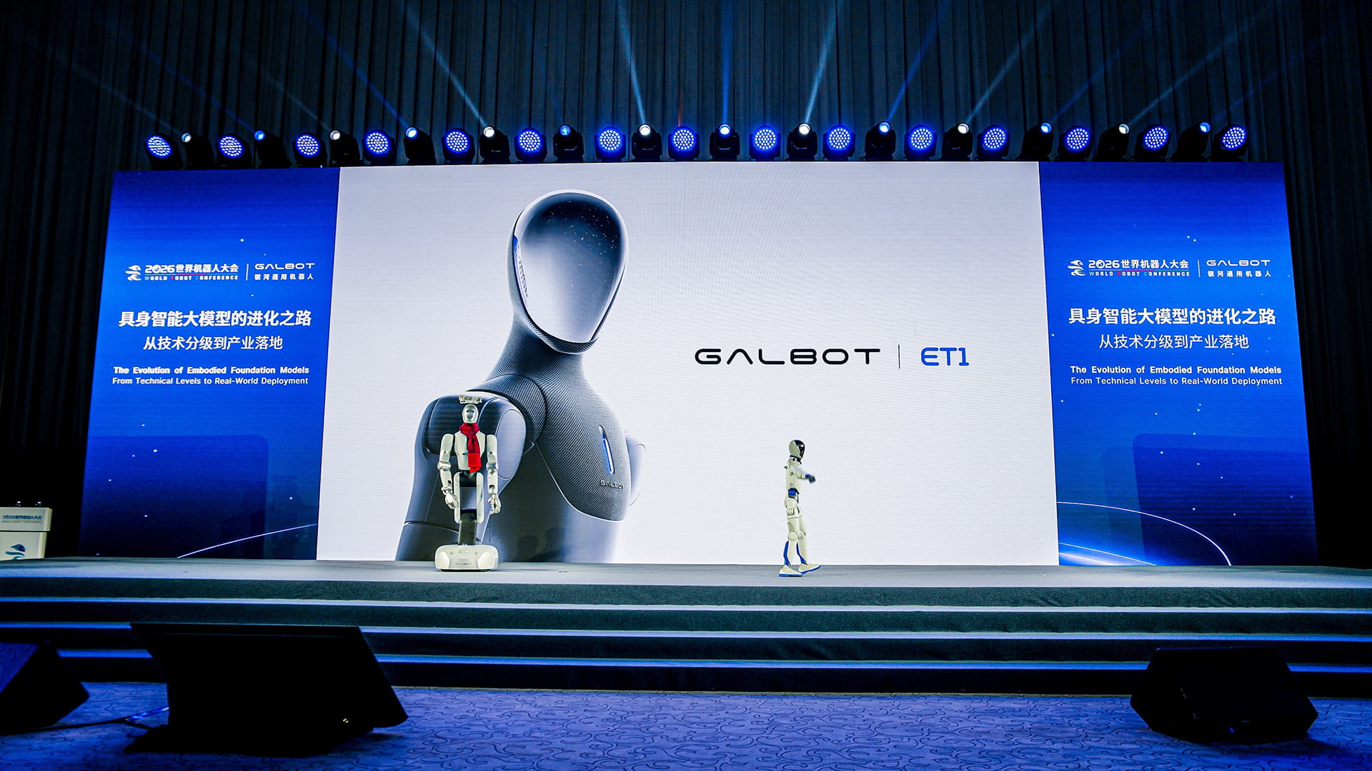 WRC 2026 stage with Galbot ET1 on screen and two robots standing in front, one with a red scarf