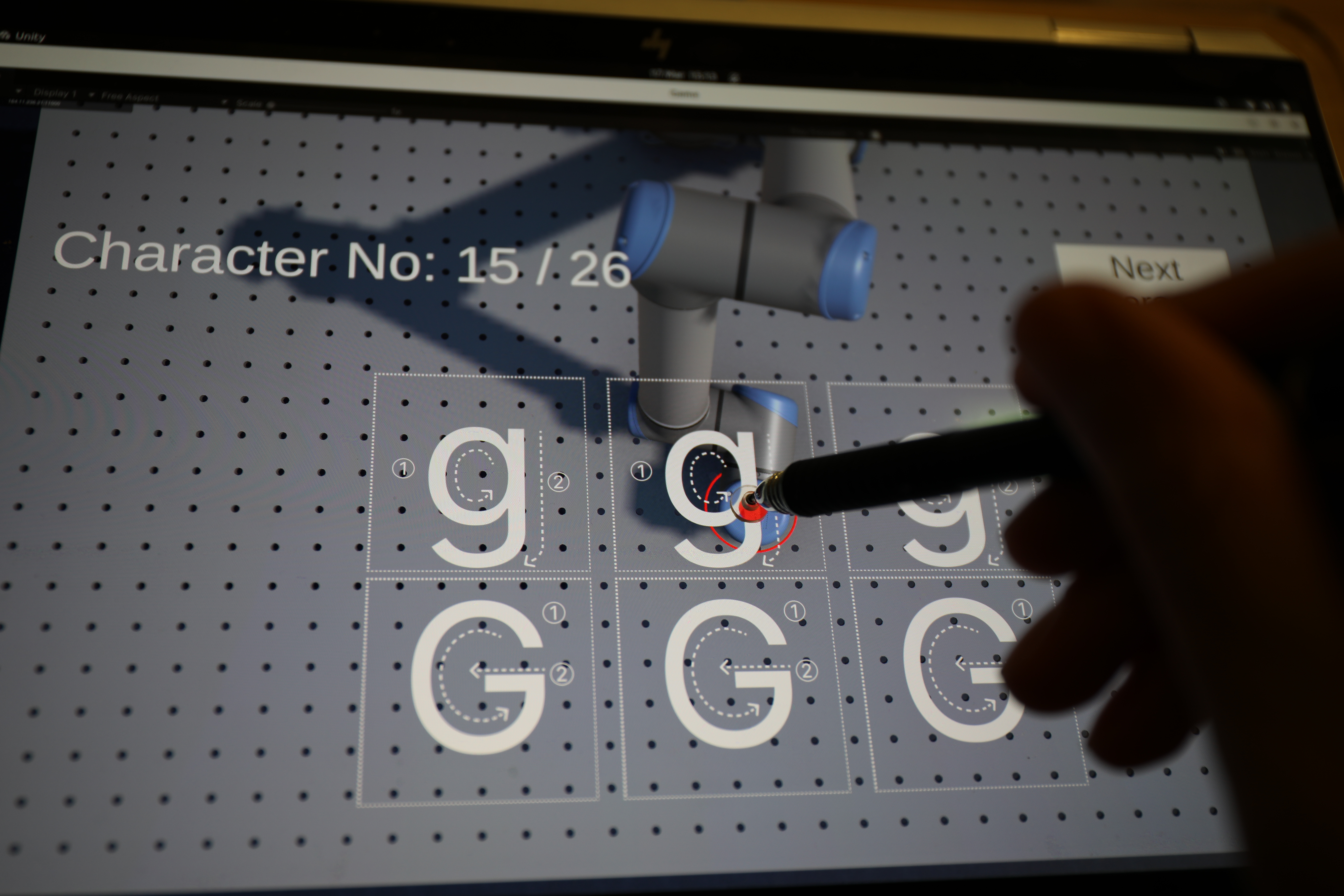 Tablet demo collection: stylus tracing letter g with robot arm visible on screen