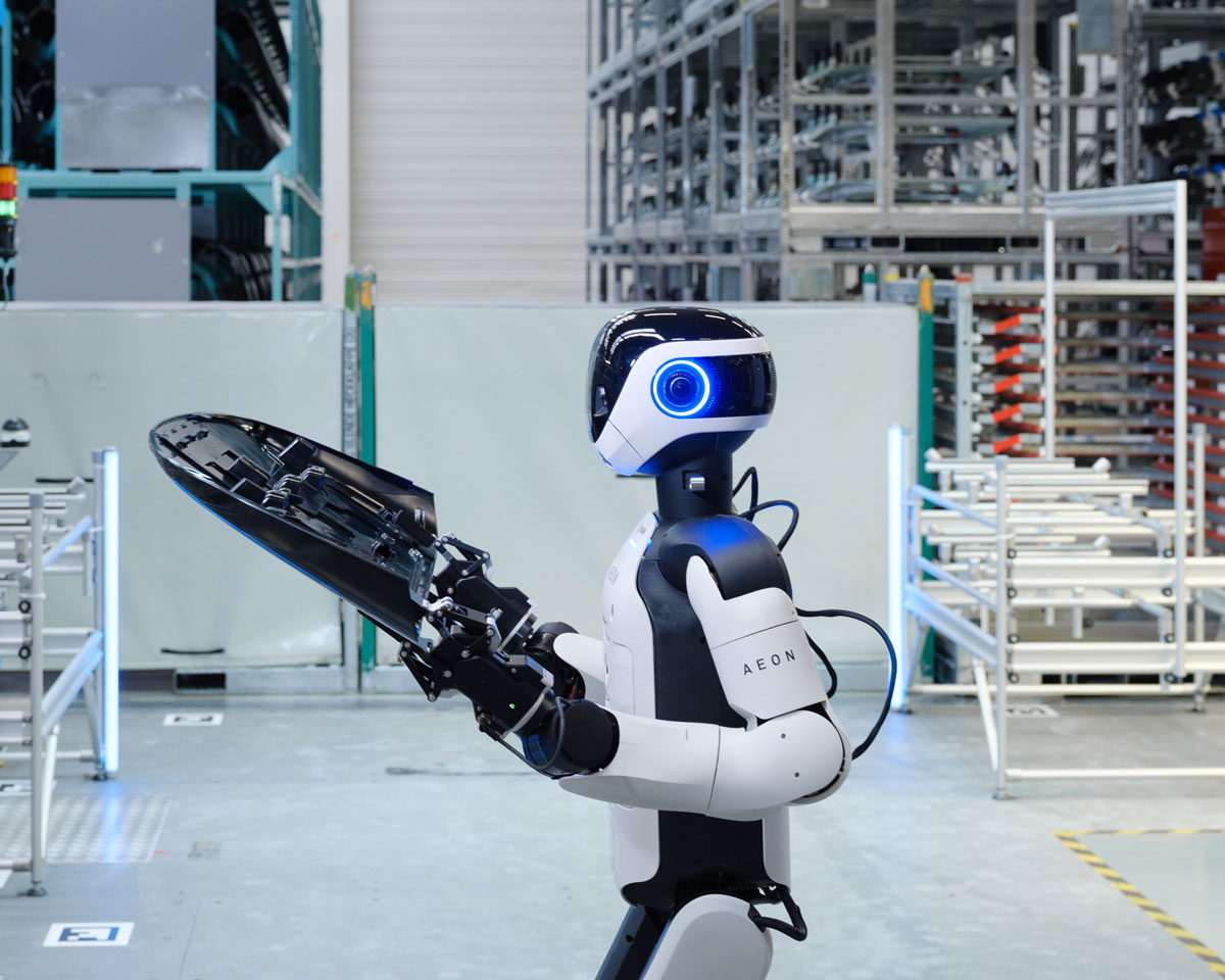 Hexagon AEON humanoid holding an automotive part in a factory