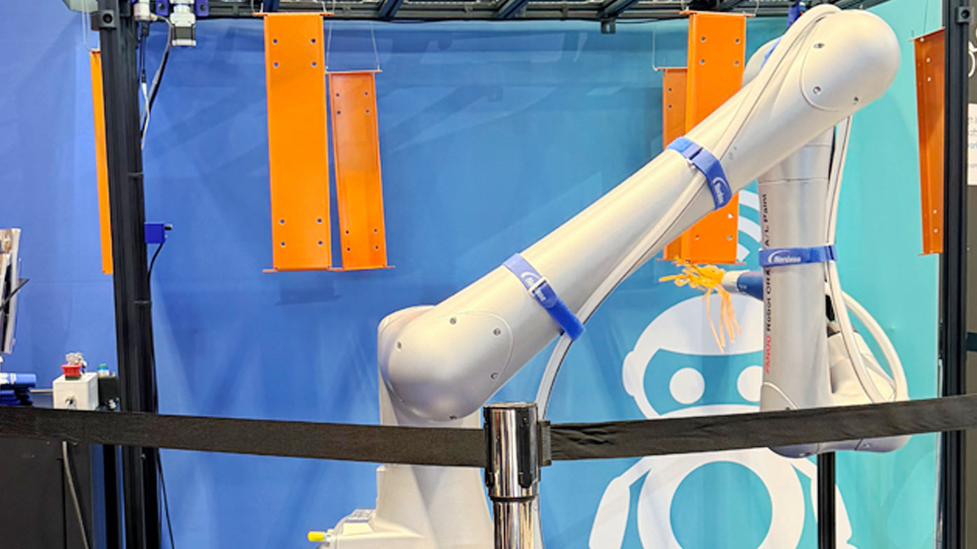 FANUC paint cobot at the Hirebotics booth reaching toward hanging orange parts