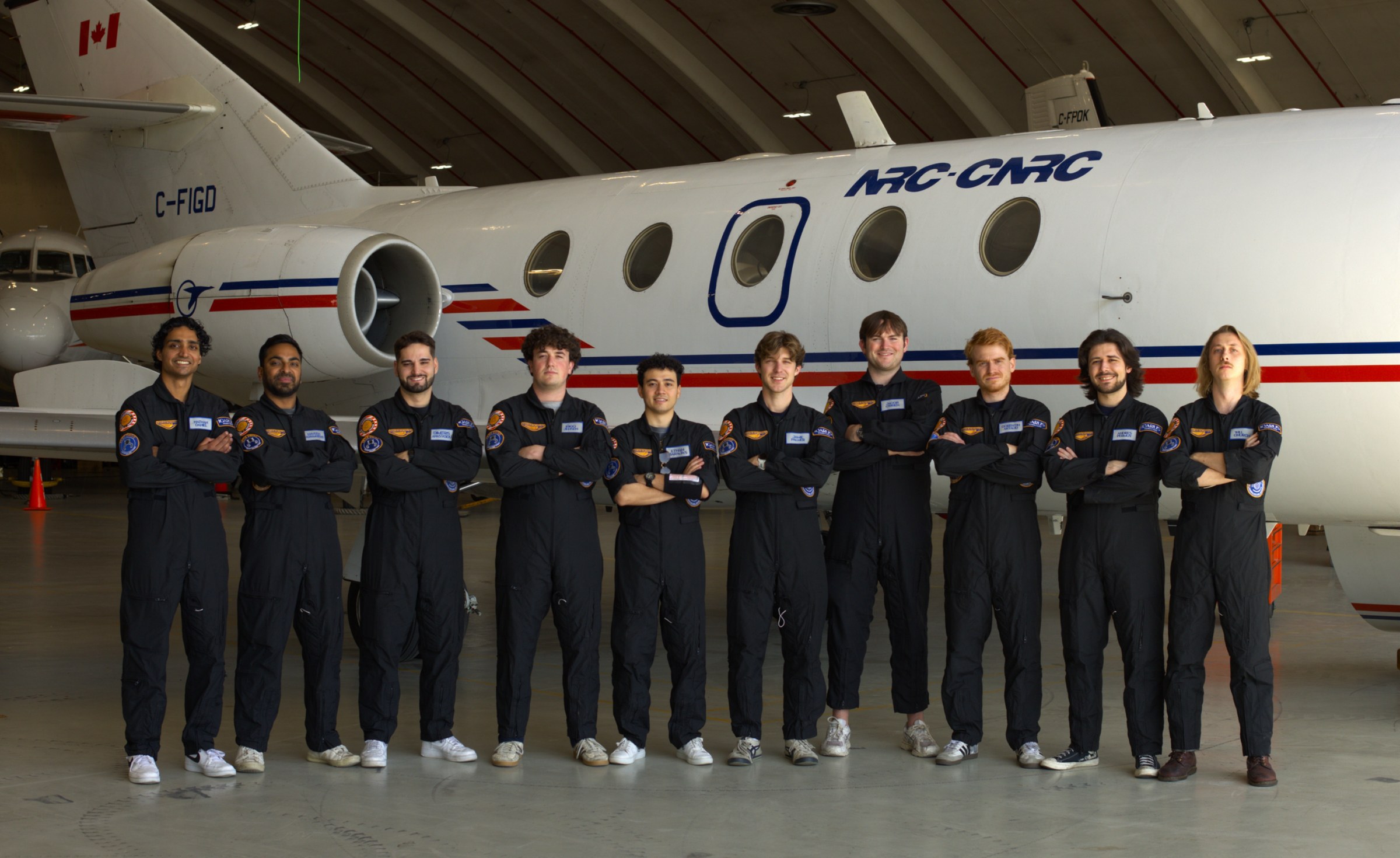 Icarus Robotics team in flight suits in front of an NRC-CNRC parabolic aircraft