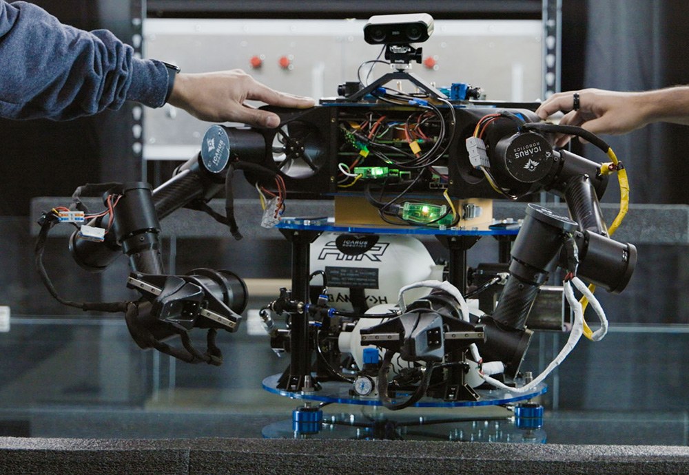 Close-up of JOY with dual carbon-fiber arms, fans, cameras, and a white tank labeled AIR