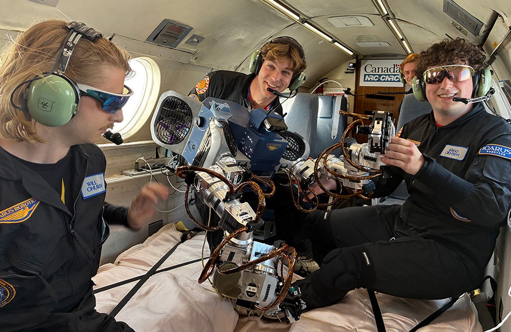 Icarus team in a parabolic-flight cabin holding JOY, a dual-arm free-flying robot