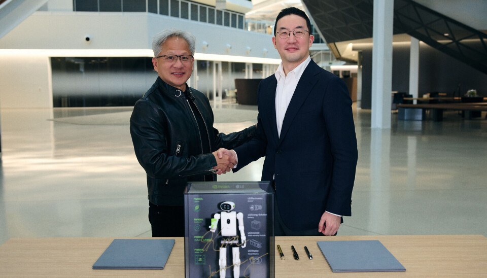 Jensen Huang and LG chairman Kwang Mo Koo shake hands over a miniature humanoid