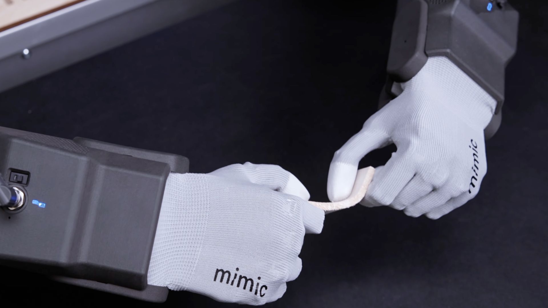 Pair of Mimic robotic hands in mesh gloves manipulating a small object