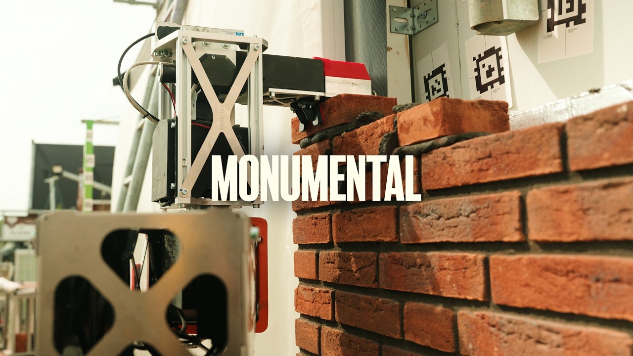 Monumental robot arm placing bricks on a red-brick wall