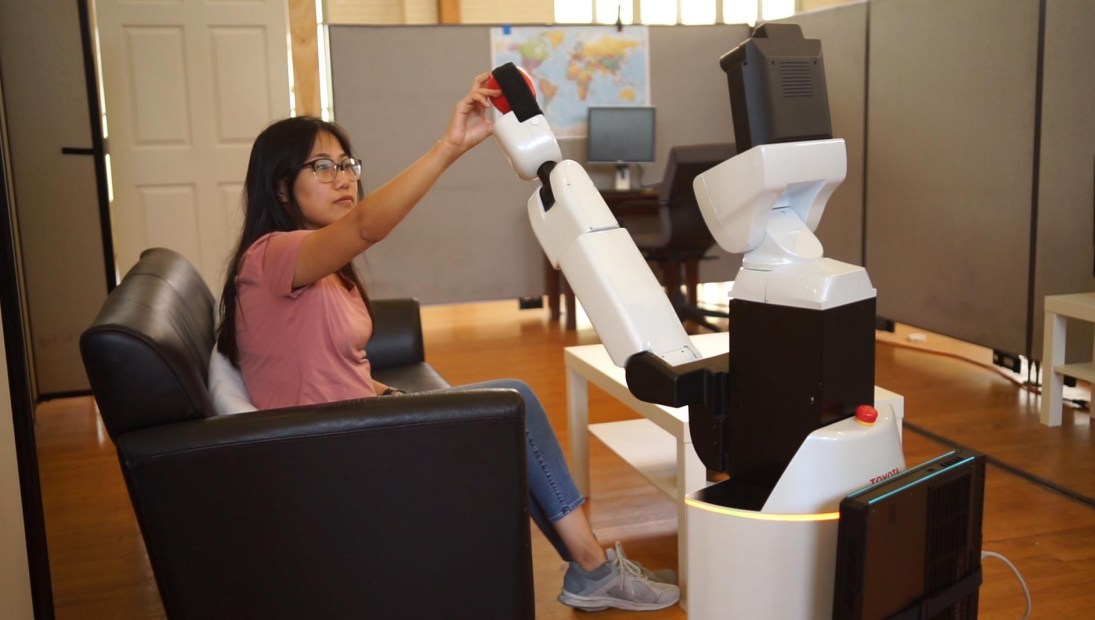 UT Austin Villa at-home Toyota HSR robot handing a red apple to a seated student