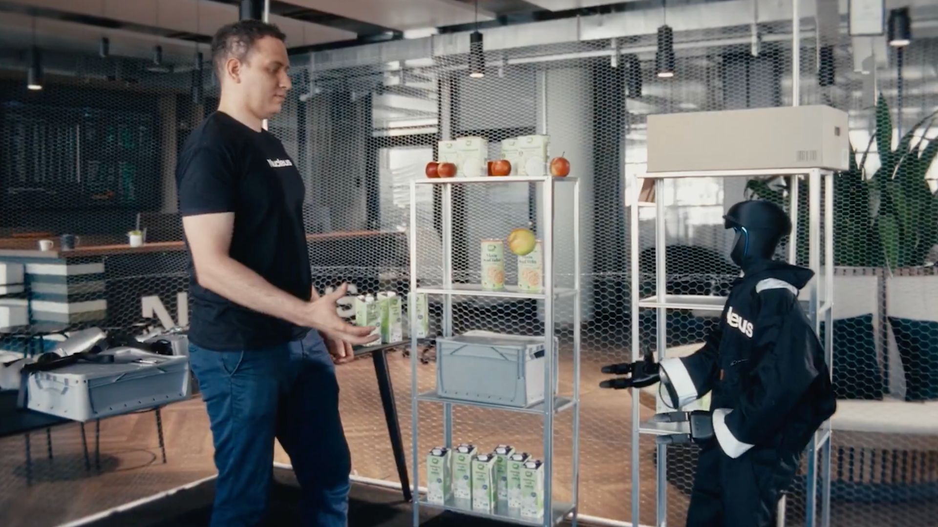 A Nucleus-suited G1 facing a man in a Nucleus shirt across two metal shelves