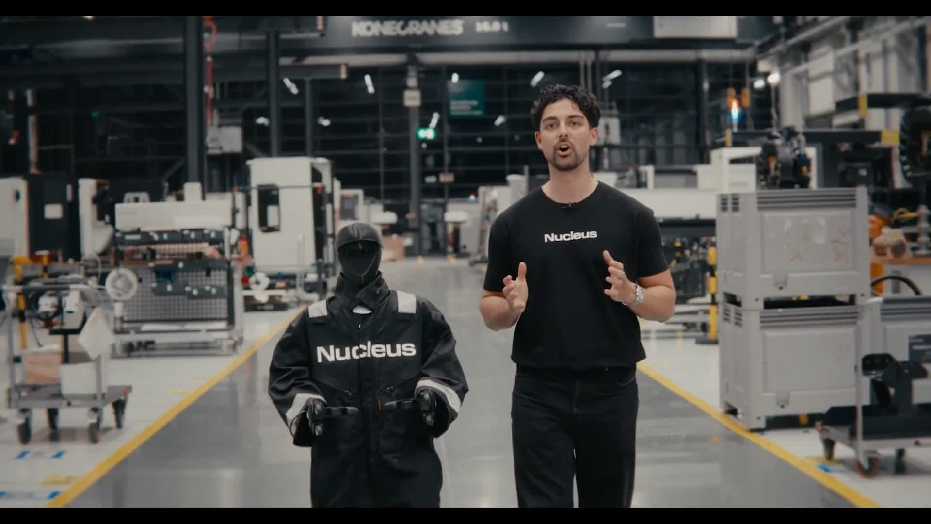 Melvin Schwarz walking a factory aisle next to a Nucleus-suited Unitree G1