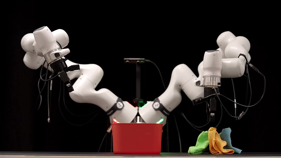 White dual robot arms over a red bin and colored cloths on a black backdrop