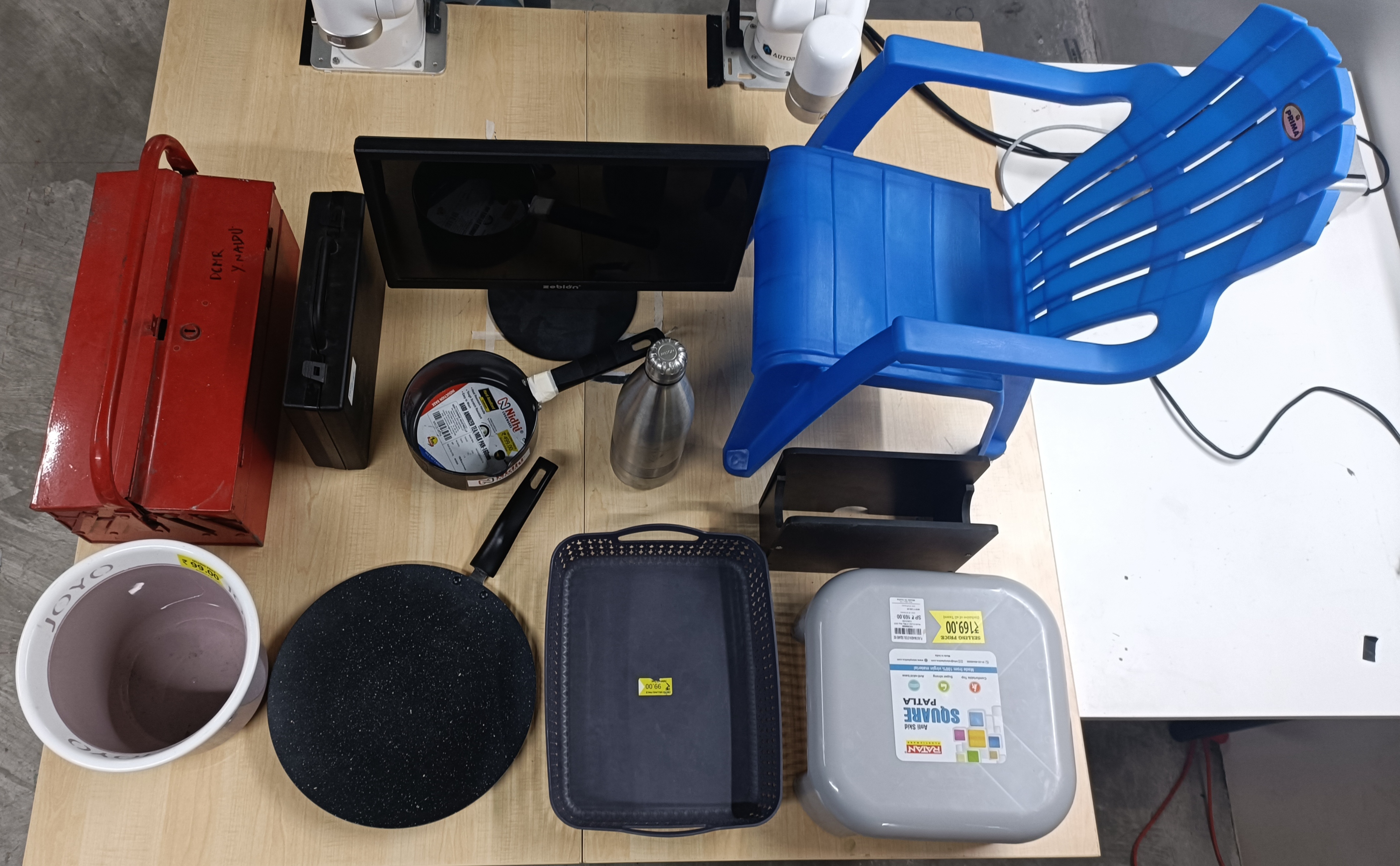 Overhead photo of a chair, toolbox, monitor, pans, bucket, and other large objects on a table