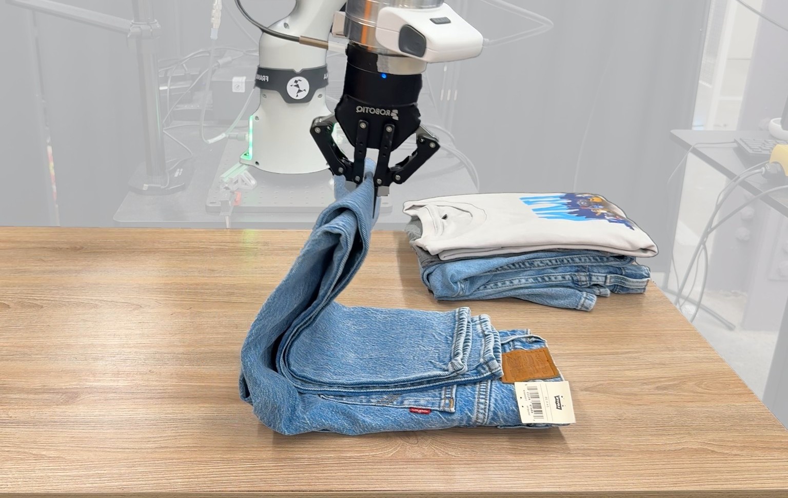 Franka arm with a Robotiq gripper folding a pair of jeans on a table