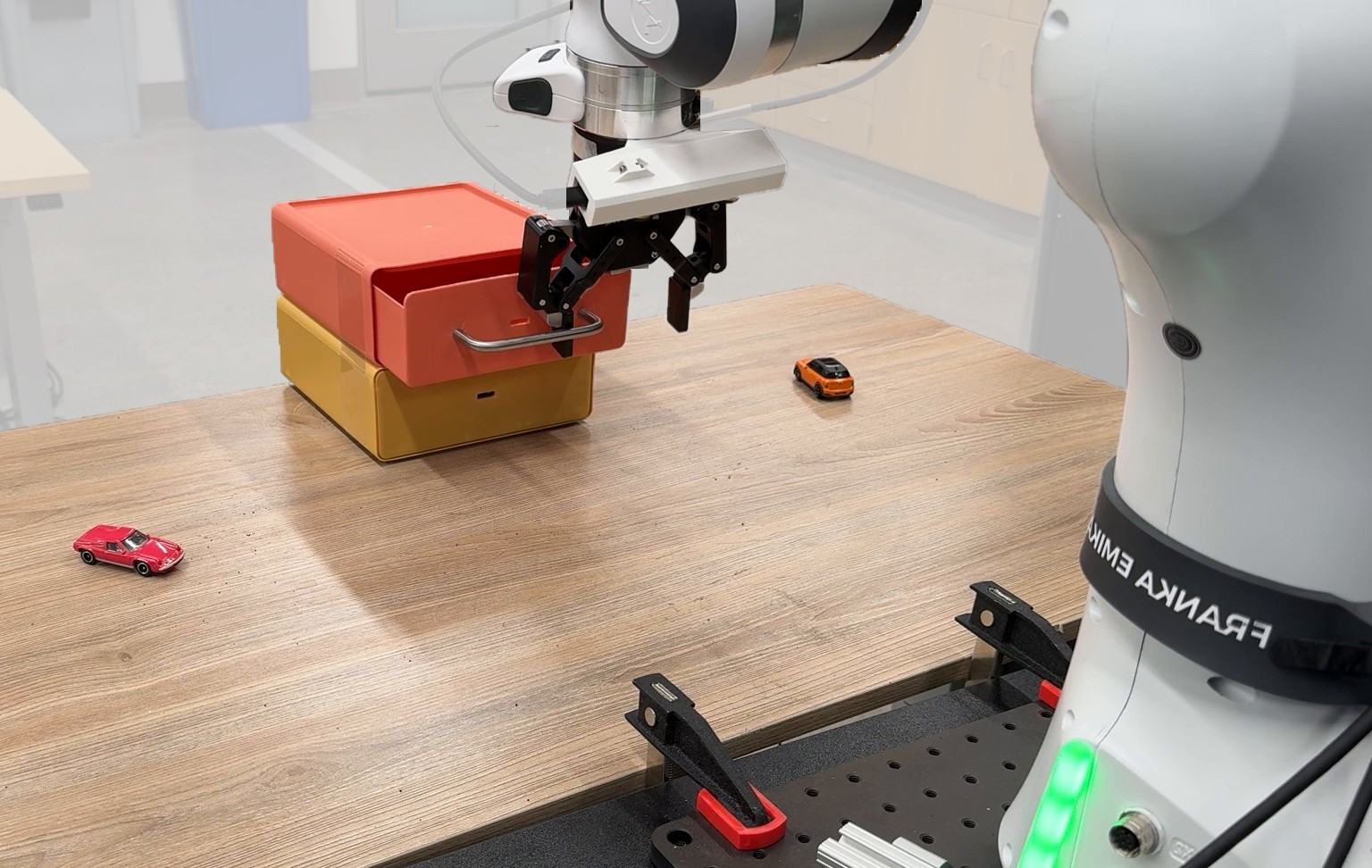 Franka Emika arm opening a stacked drawer box on a table with toy cars
