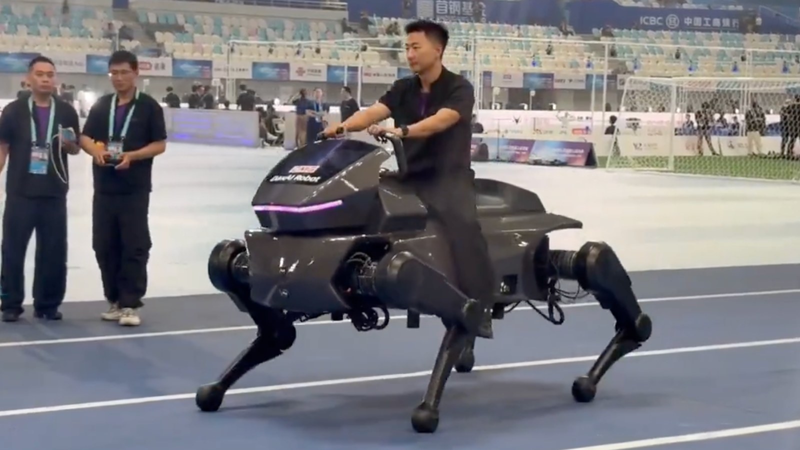 A person riding DaxAI’s Qiji X1 four-legged robot horse on a blue indoor track
