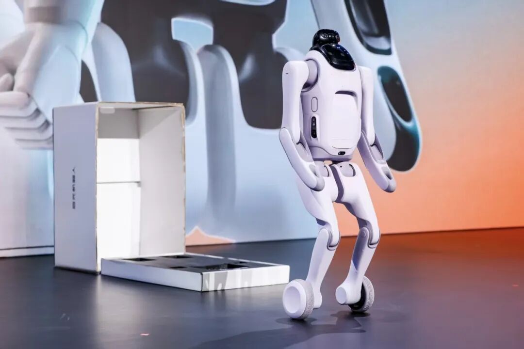 Qiyuan T1 wheeled humanoid standing on a dark stage next to an open shipping box