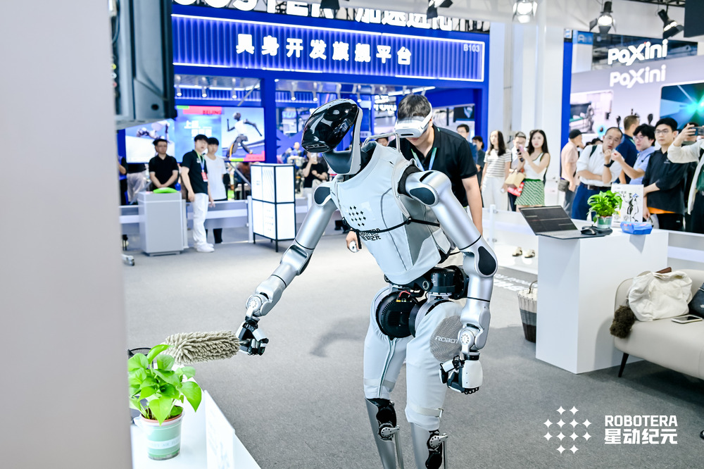 ROBOTERA L7 at WRC 2026 reaching toward a plant while a teleoperator stands behind it