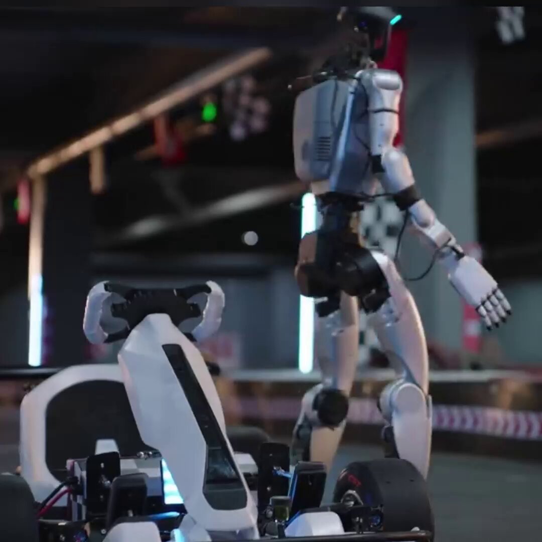 A silver-and-white bipedal humanoid standing next to an empty go-kart