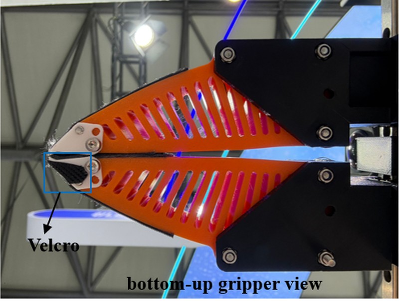 Orange 3D-printed gripper with Velcro on the fingertip, viewed from below