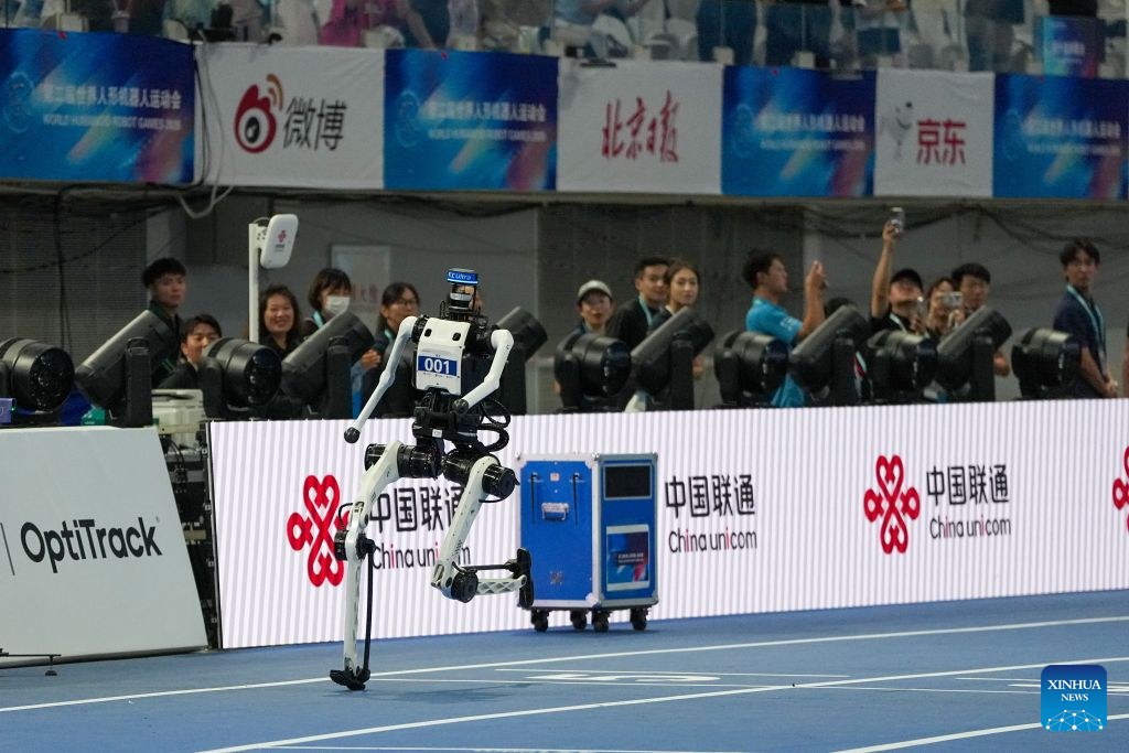 Close-up of humanoid bib 001 running past China Unicom boards at the World Humanoid Robot Games
