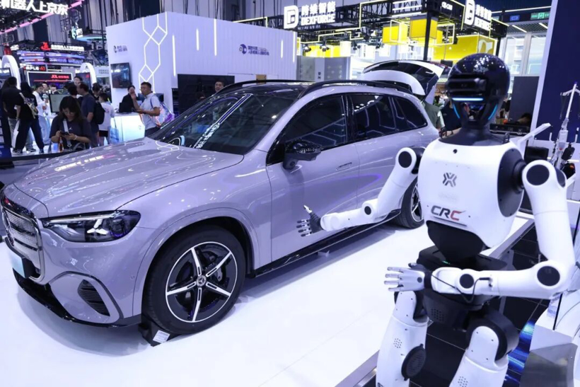 A full-size white X-Humanoid standing beside a silver Mercedes wagon on a WRC show floor