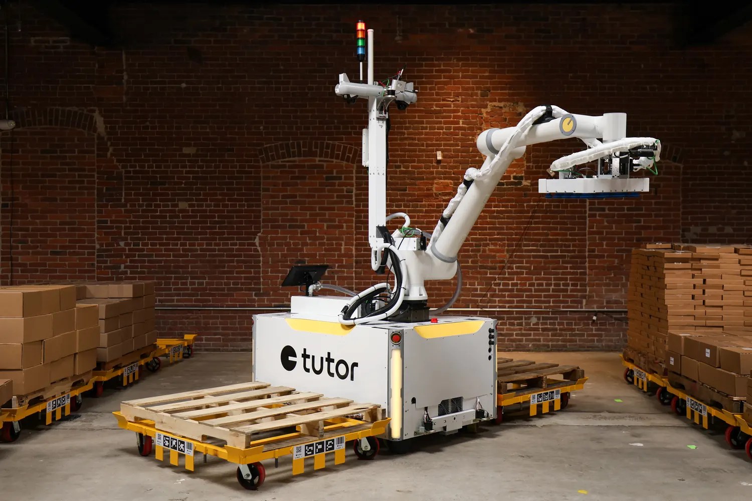 Tutor Cassie mobile arm on a wheeled base with a vacuum gripper above pallets