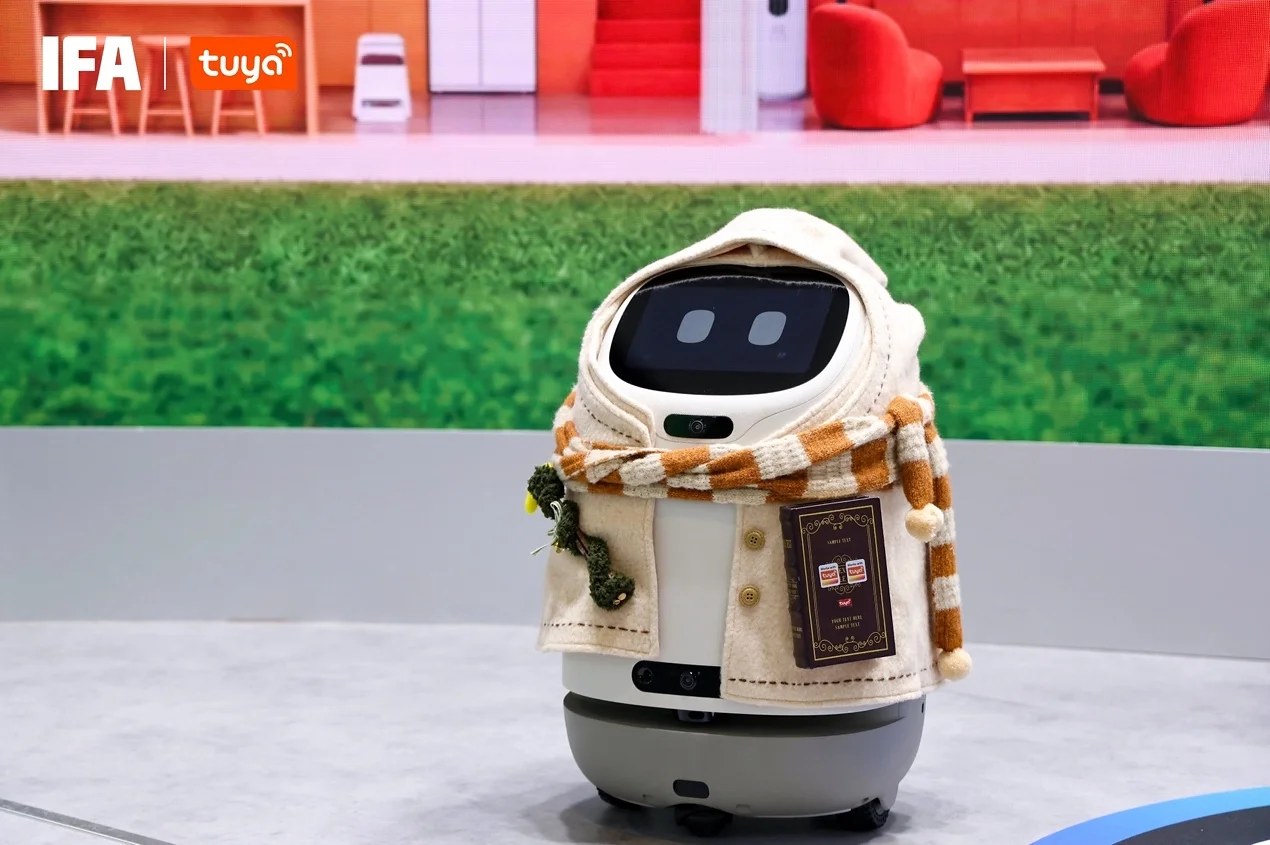 Doova at IFA 2026 in a knitted hood and striped scarf, screen face and caster base visible