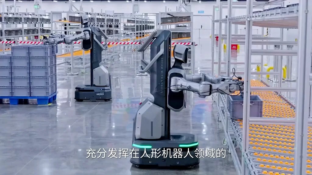 Two wheeled Cruzr dual-arm robots handling totes along roller racks in a factory aisle