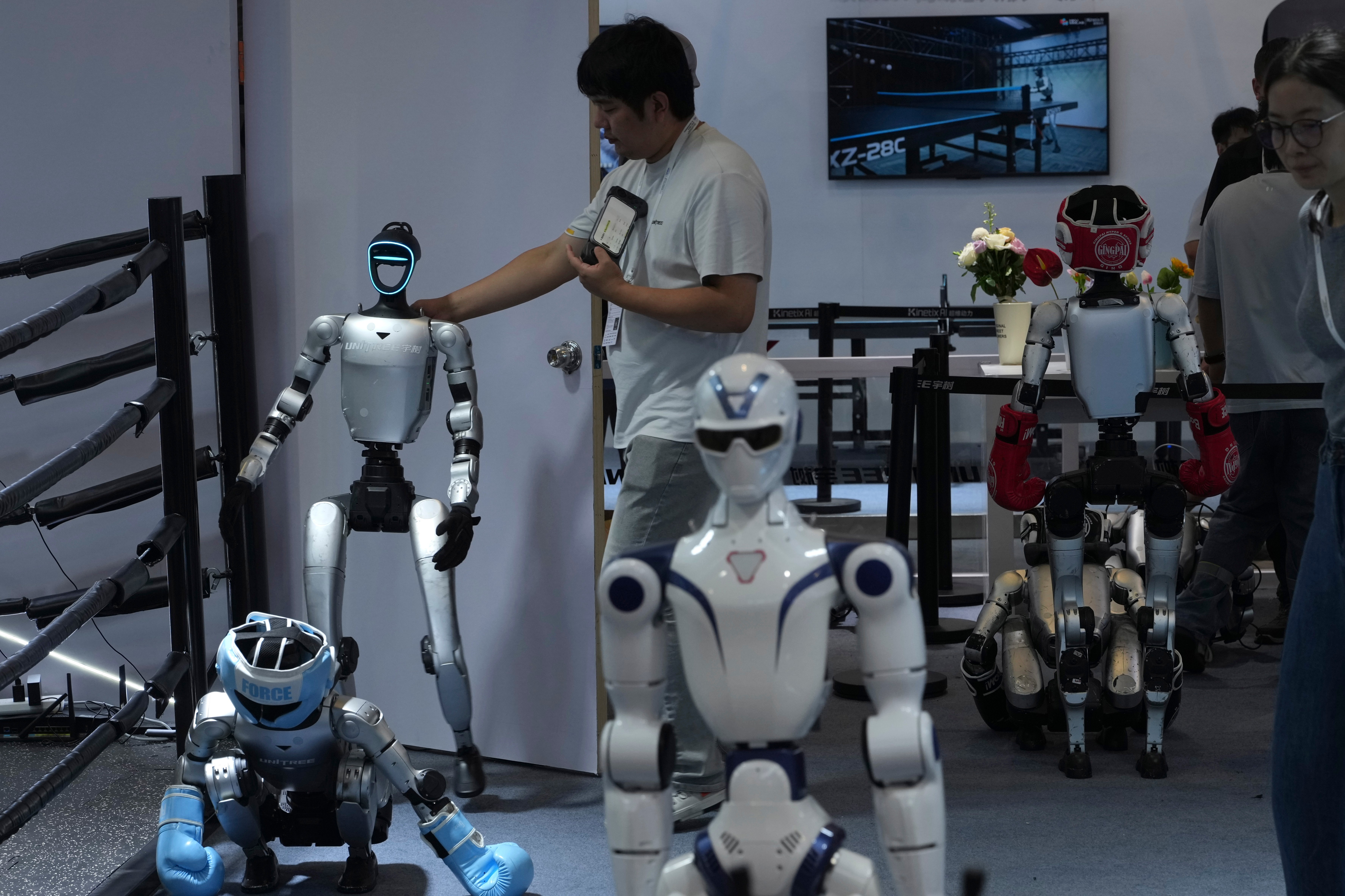 Unitree staff with humanoid robots in boxing gear at the World Robot Conference booth in Beijing