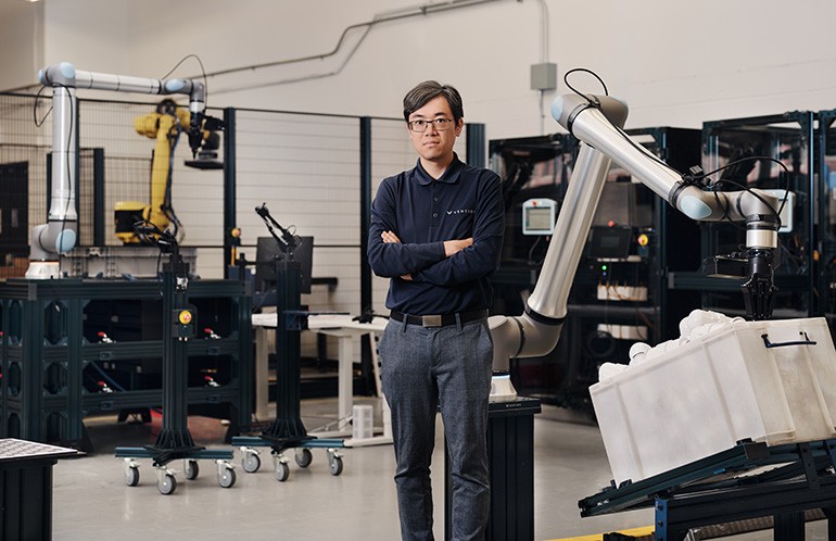 Jimmy Li standing between robot arms in Vention’s Montreal lab