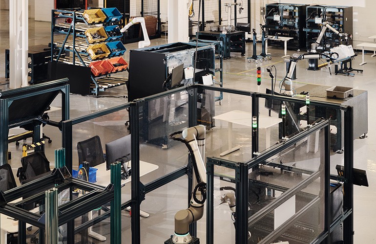 Vention Physical AI Lab floor with robot-arm cells, bins, and safety fencing