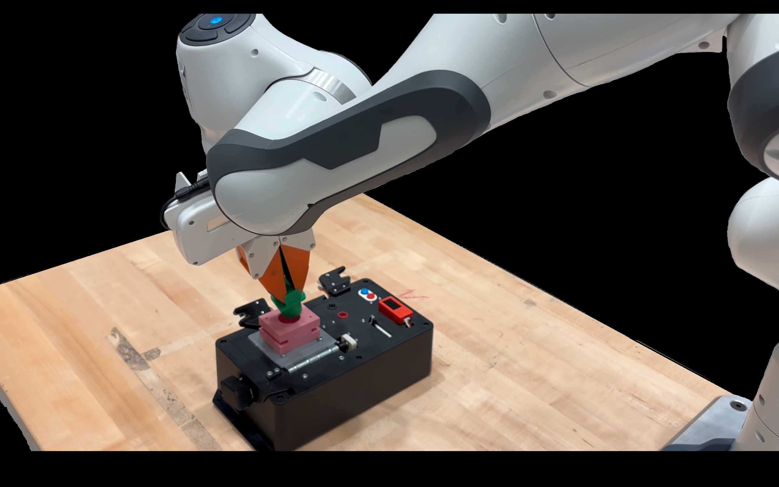 Robot arm with orange gripper performing contact-rich insertion on a wooden table fixture