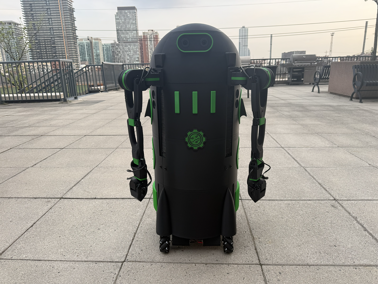 Sourccey black and green wheeled dual-arm robot on a rooftop terrace