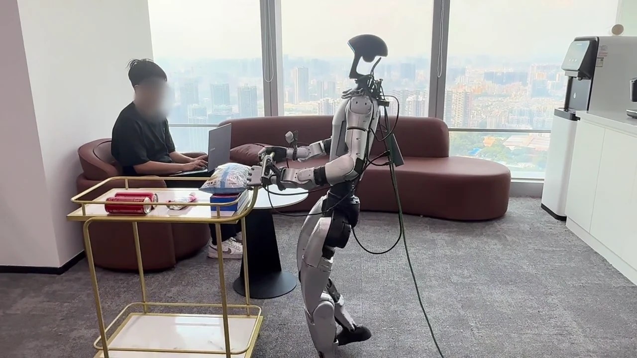 Unitree G1 humanoid pushing a serving cart toward a person on a sofa