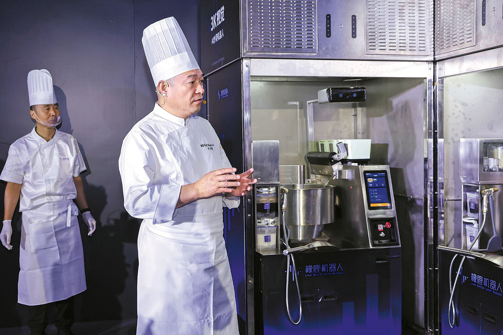 Chefs standing beside Xianglu’s 3K Vision wok station at a World Robot Conference booth