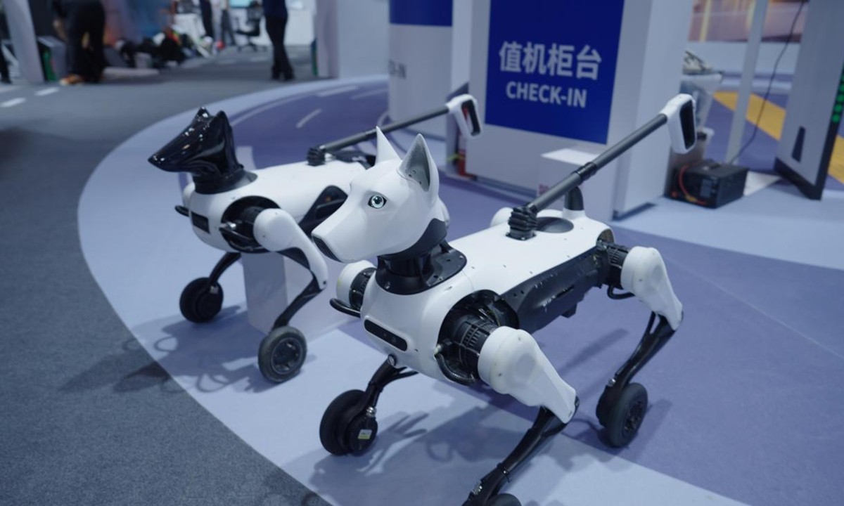 Two Xiaoyuan wheeled-legged guide robots on a show floor with leash handles